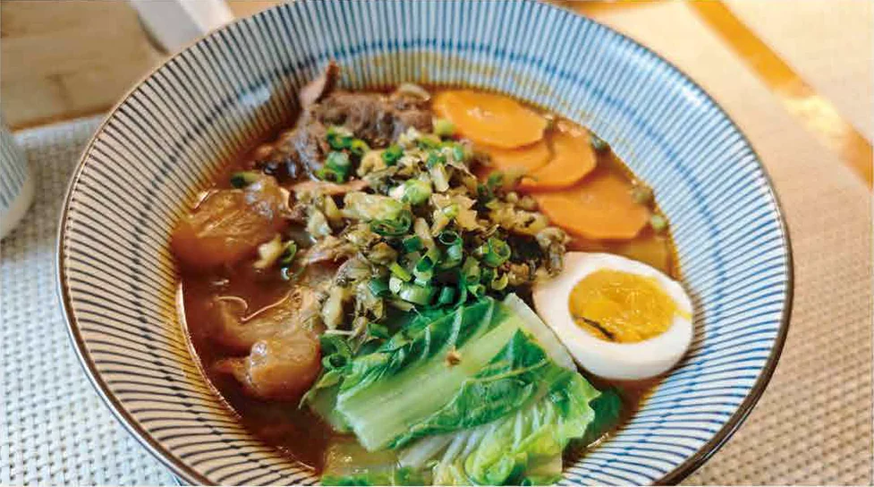 Another bowl of Grandma Lin's beef noodle soup with a soft-boiled egg, carrot and greens